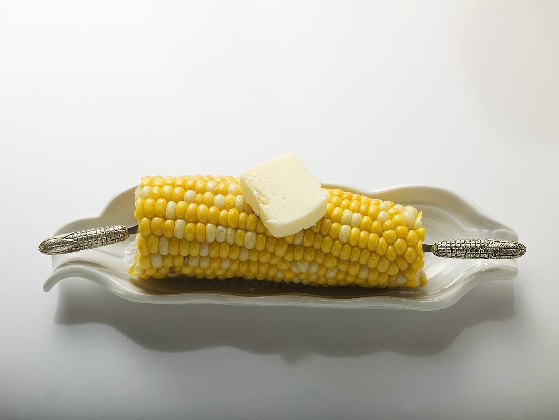 Corn cob with knob of butter in white dish