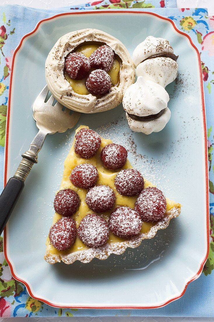 Stück Himbeertarte, Baisertörtchen und Schaumgebäck