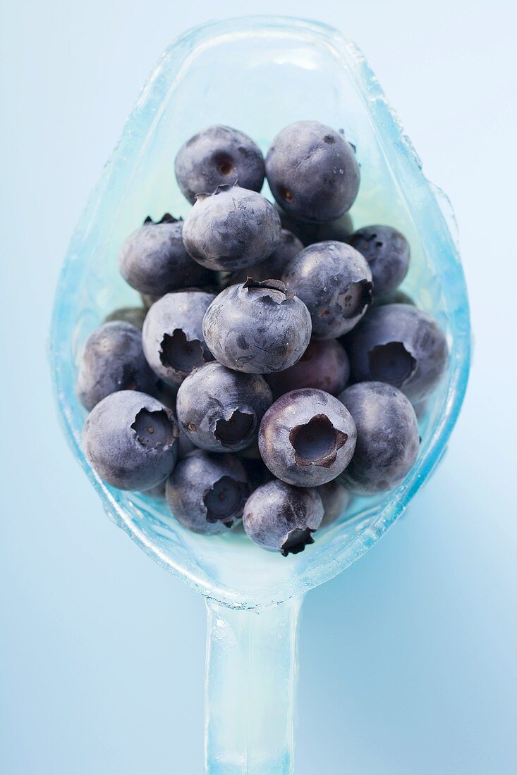 Fresh blueberries in light blue glass jug (overhead view)