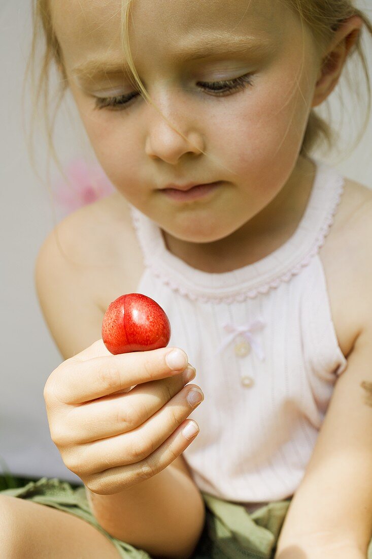 Small girl holding a cherry