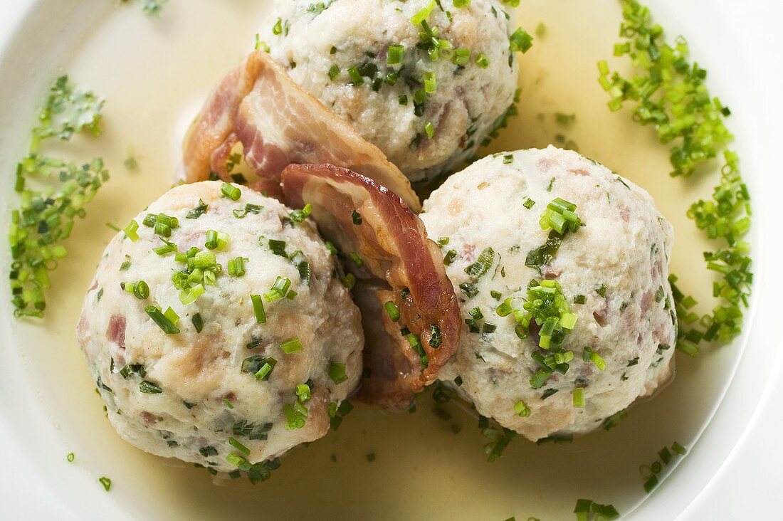 Clear broth with bacon dumplings in soup plate (detail)