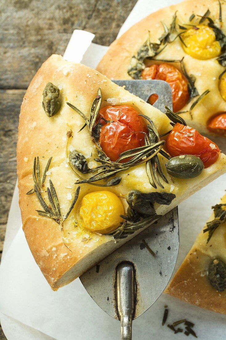 Pizza mit Kirschtomaten, Kapern und Rosmarin (angeschnitten)