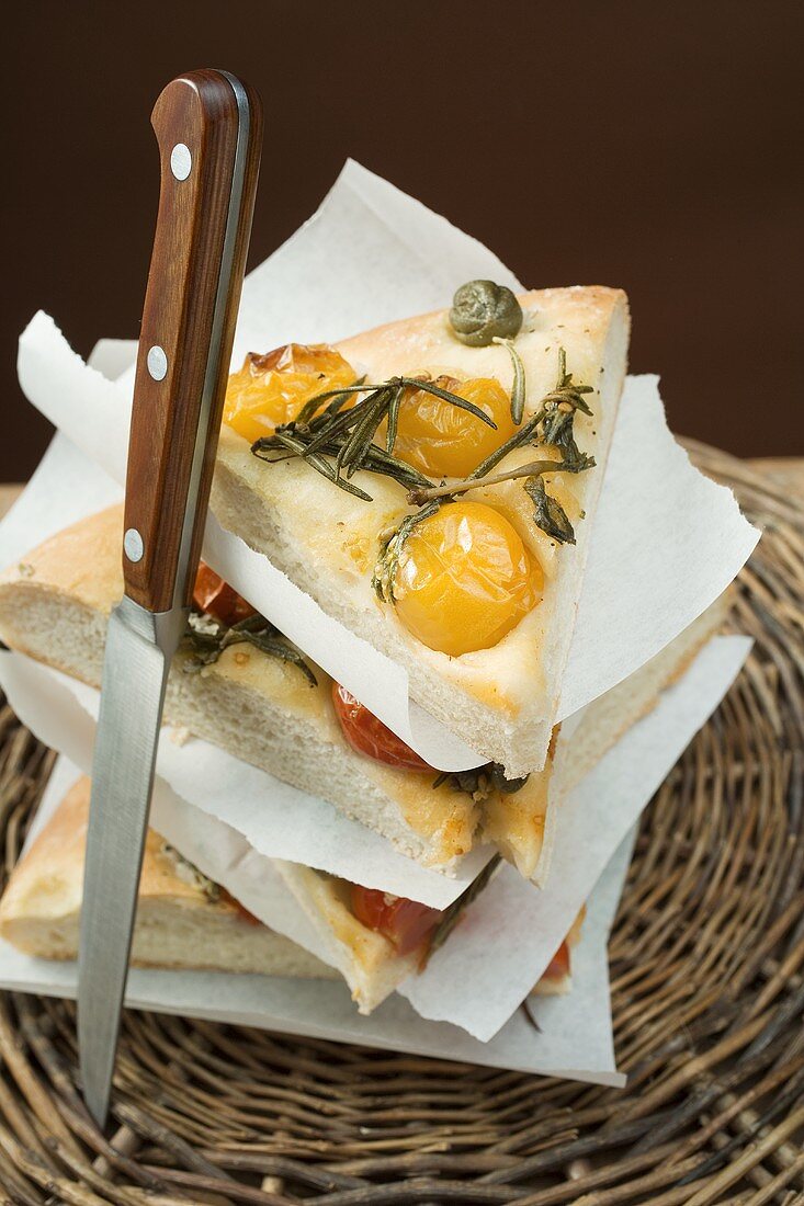 Slices of pizza with cherry tomatoes, capers and rosemary