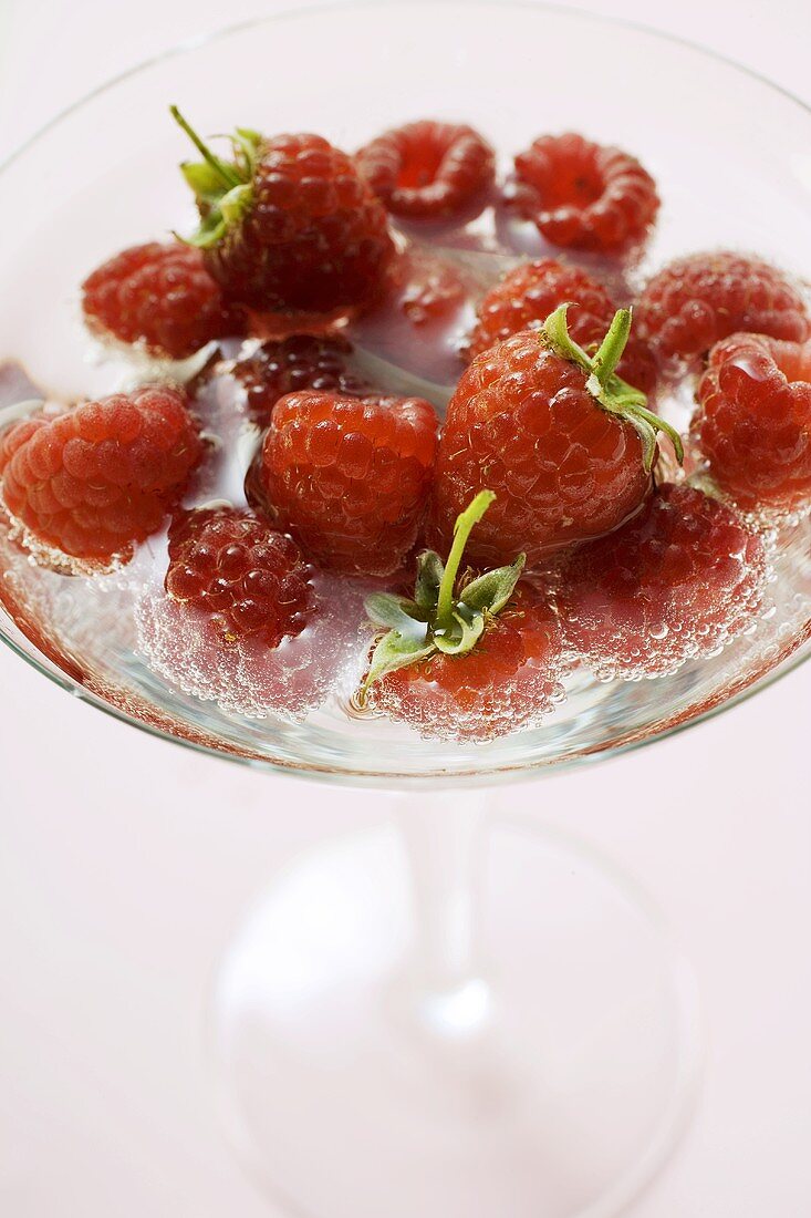 Fresh raspberries in water in a cocktail glass