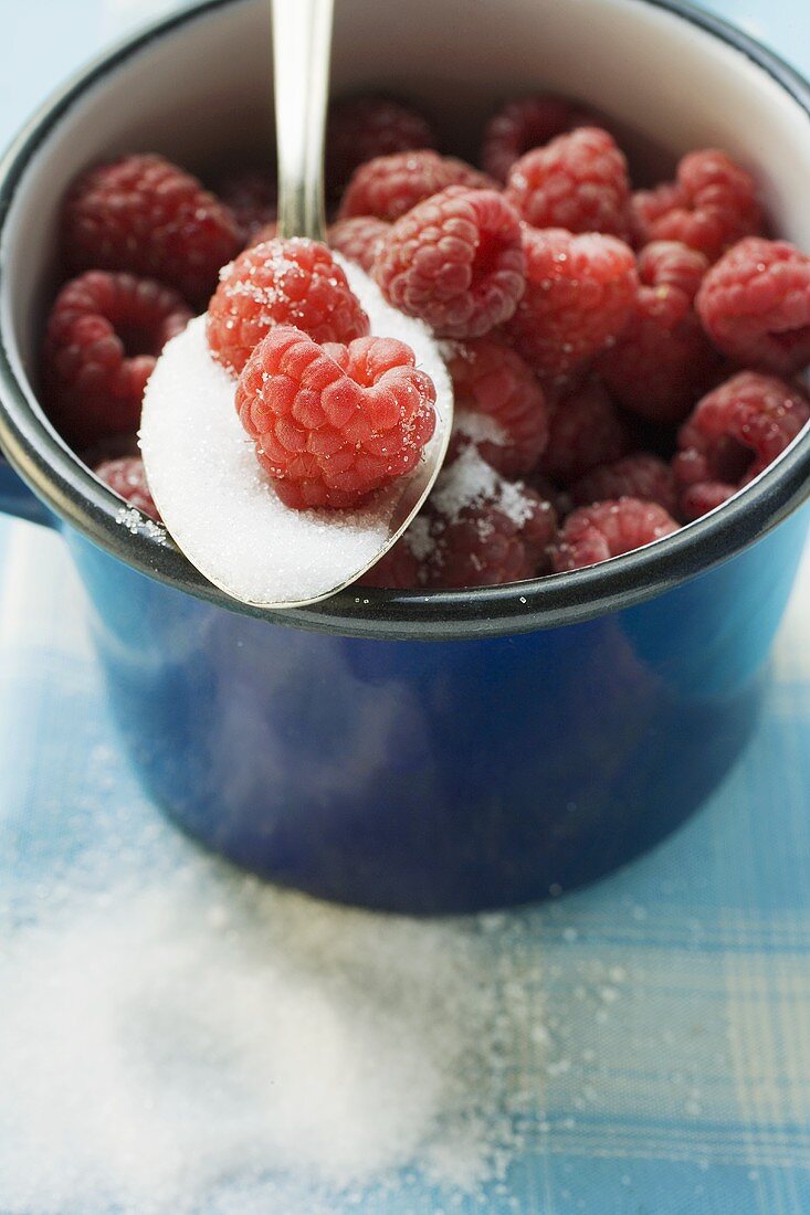 Raspberries in a pan with a spoonful of sugar