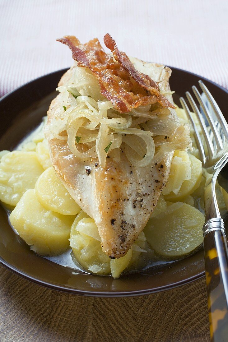 Chicken breast with bacon and onions on potato salad