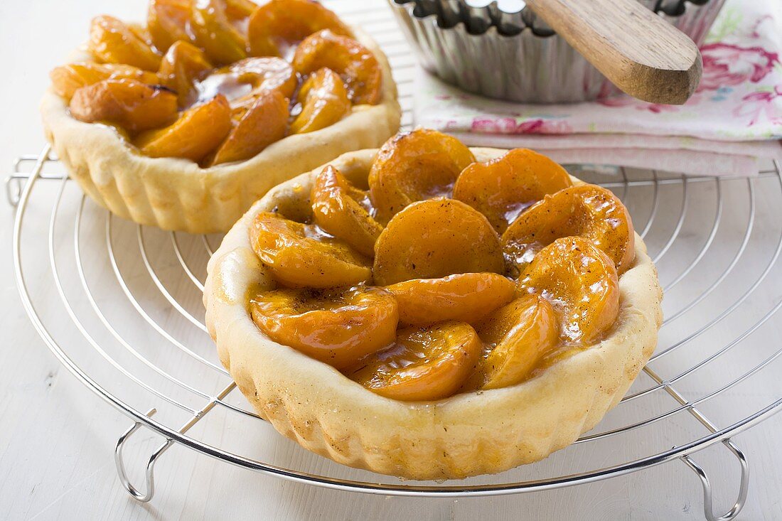 Two apricot tarts on cake rack