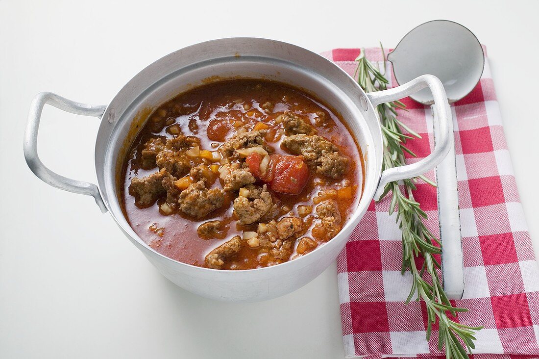 Hackfleischragout im Kochtopf, daneben Rosmarin