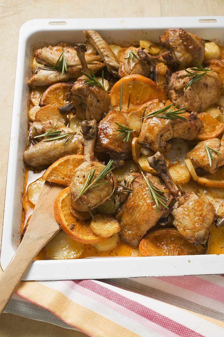 Chicken pieces with oranges and rosemary on baking tray