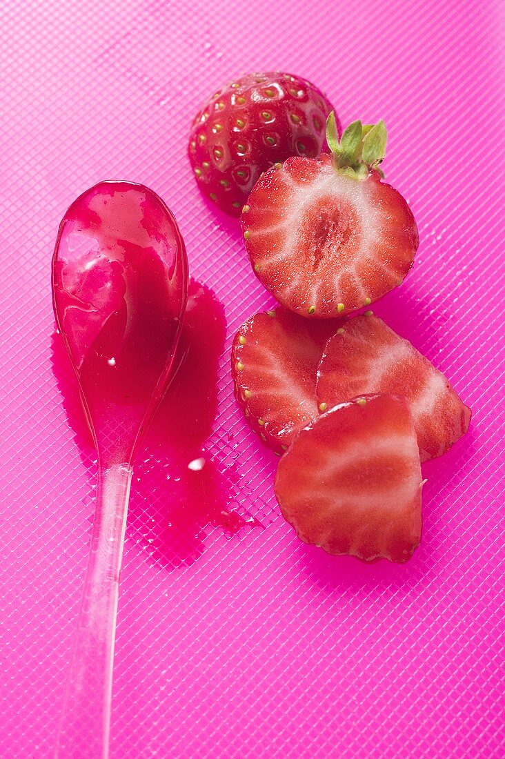 Ein Löffel Erdbeermarmelade, daneben frische Erdbeeren