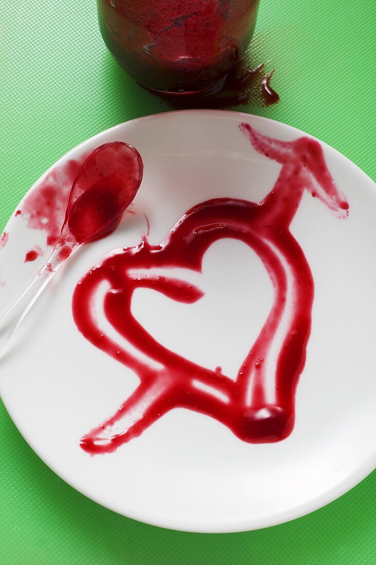 Heart drawn in strawberry jam on plate