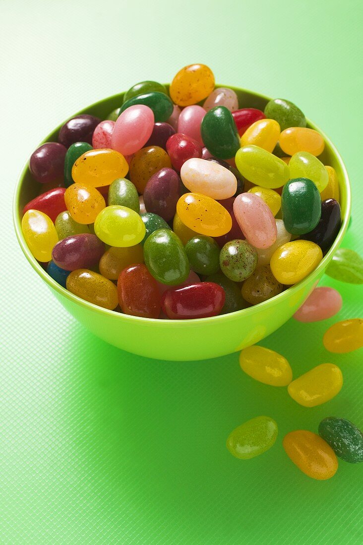Coloured jelly beans in and beside green bowl