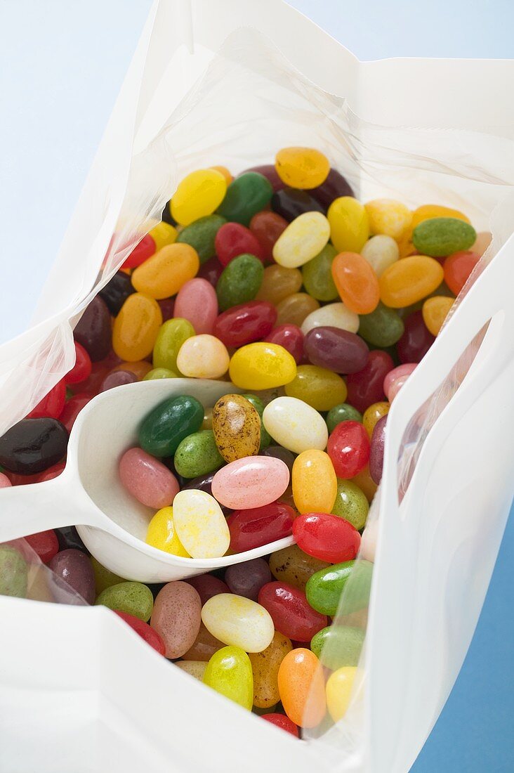 Coloured jelly beans in plastic bag with scoop (detail)