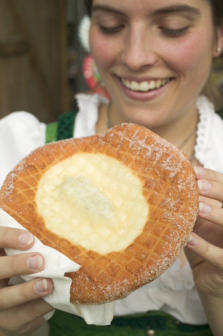 Woman eating Auszogene (type of doughnut) at Oktoberfest