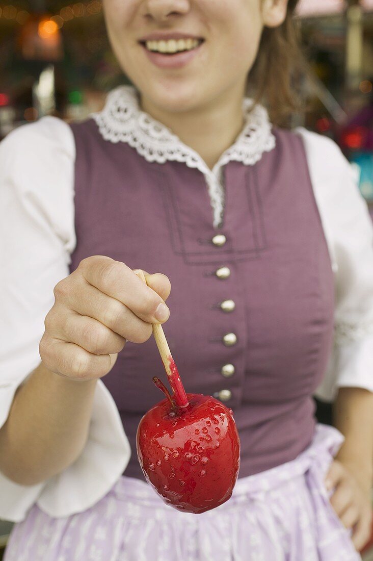 Frau hält Liebesapfel in der Hand beim Oktoberfest