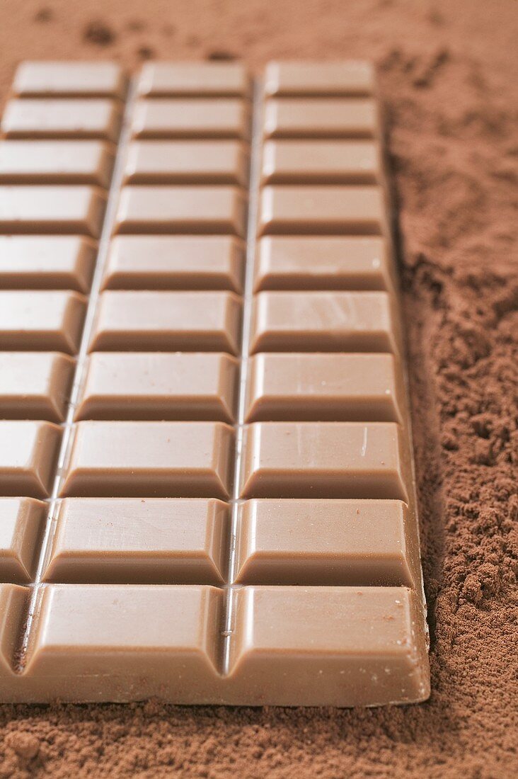 Eine Tafel Vollmilchschokolade auf Kakaopulver