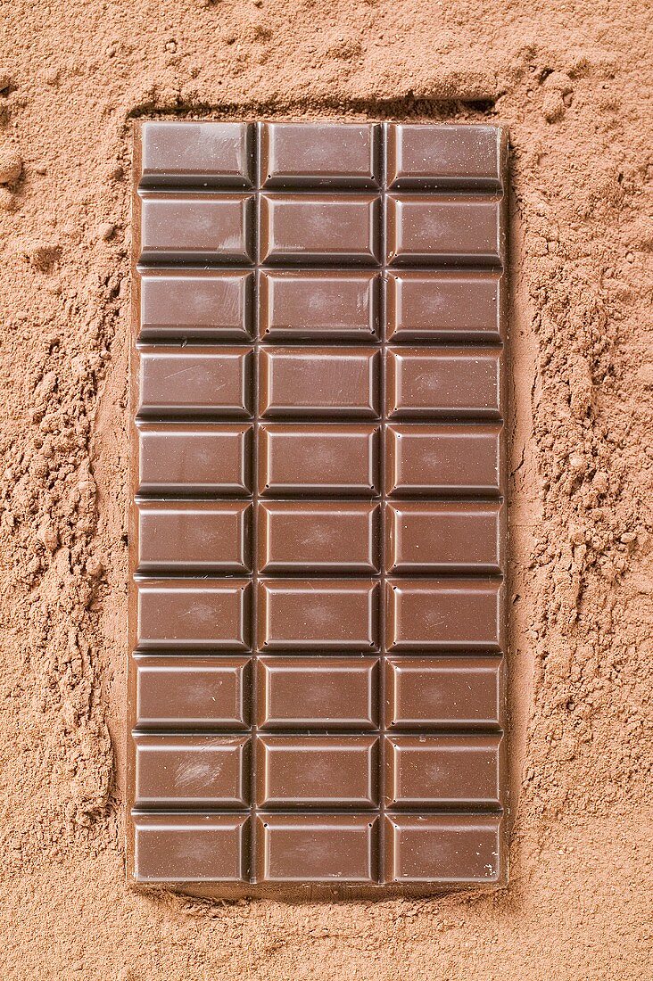 Eine Tafel Zartbitterschokolade auf Kakaopulver