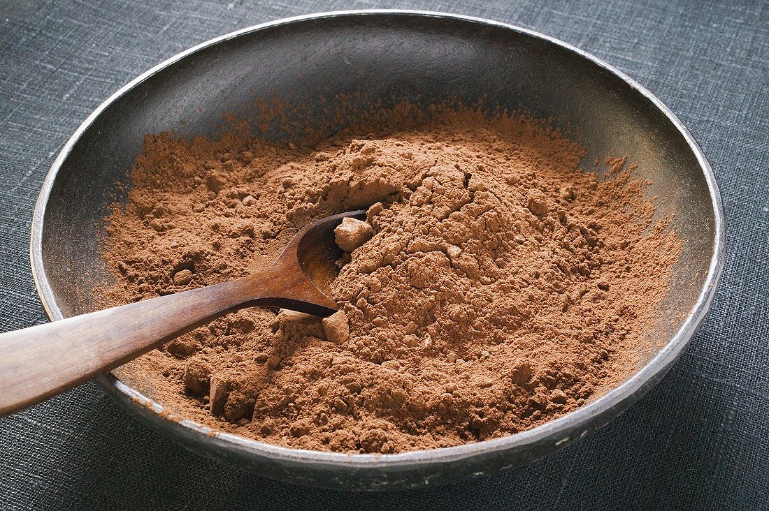 Kakaopulver in Schale mit Holzlöffel
