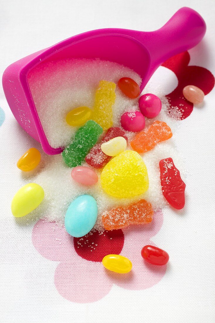 Sweets and sugar in front of upset plastic scoop
