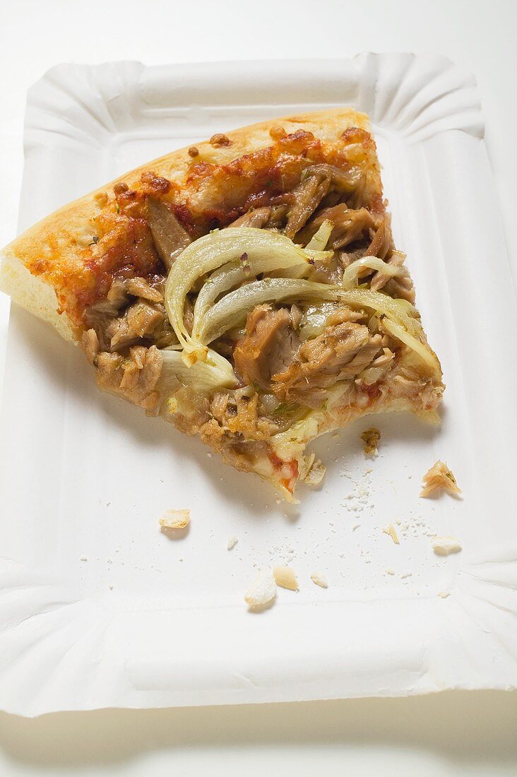 Stück Thunfisch-Zwiebel-Pizza auf Pappteller (angebissen)