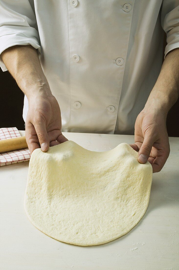 Pizzateig mit den Händen formen (ausziehen)