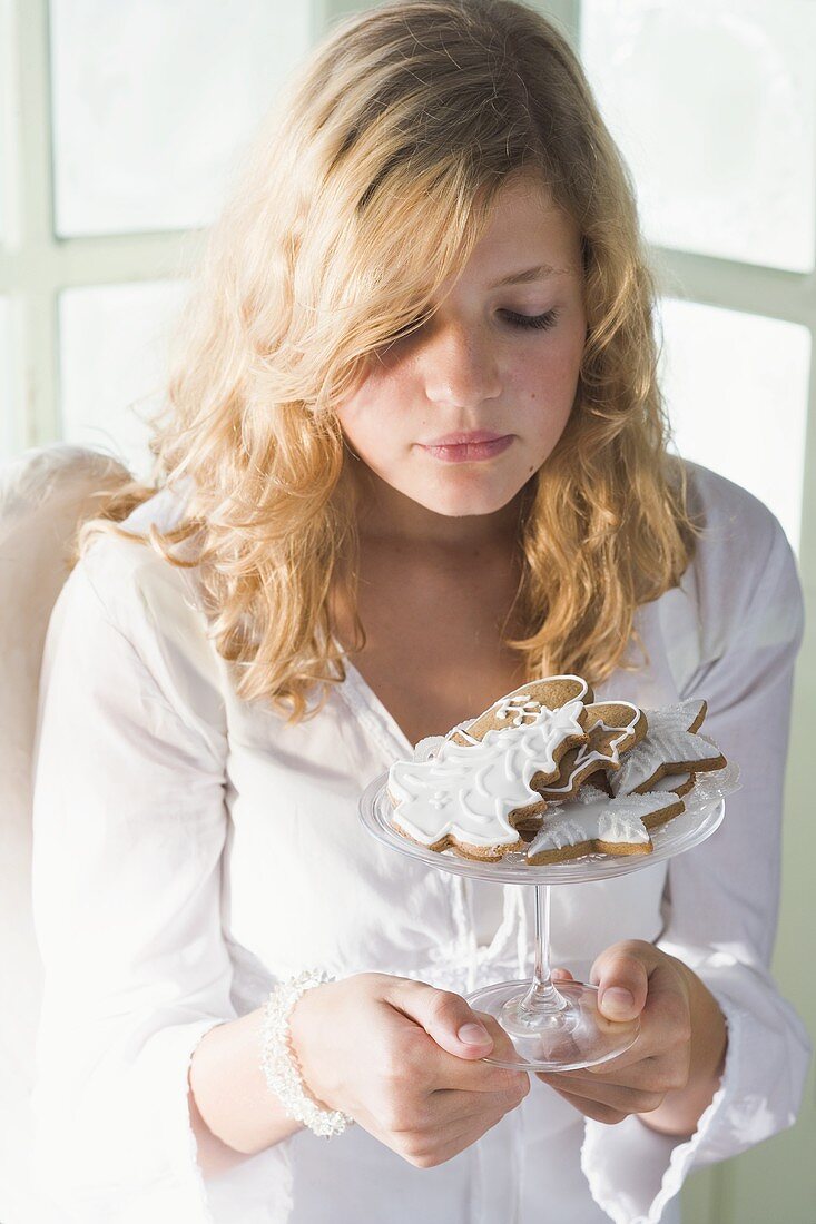 Blondes Mädchen hält Glasschale mit verschiedenen Lebkuchen