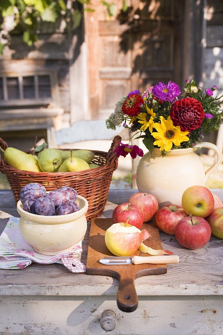 Rustic fruit still life on garden table in front of farmhouse
