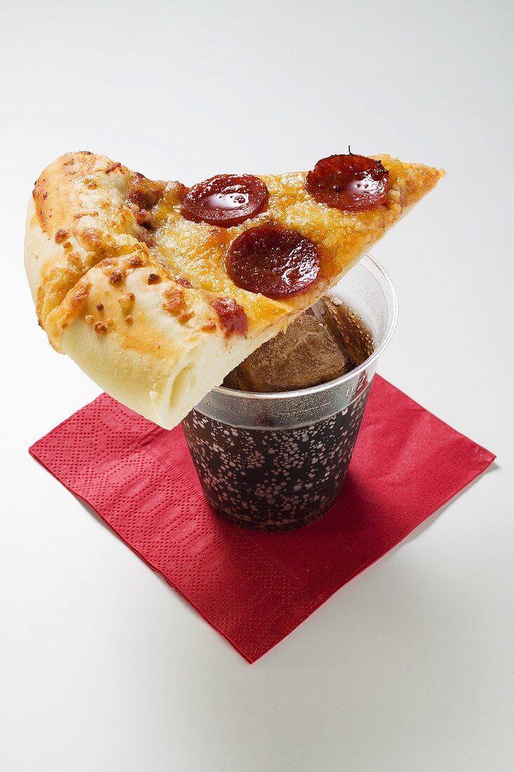 Stück Pizza mit Peperoniwurst (amerikanische Art) auf Cola