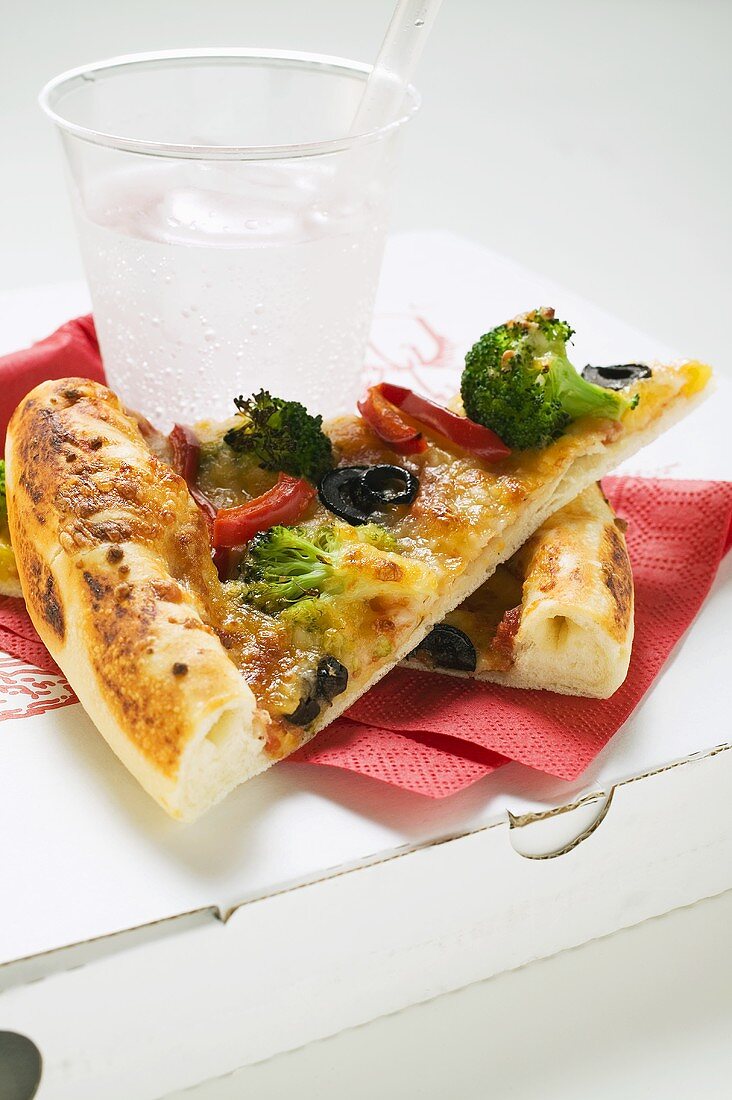 Two slices of American-style vegetable pizza, mineral water