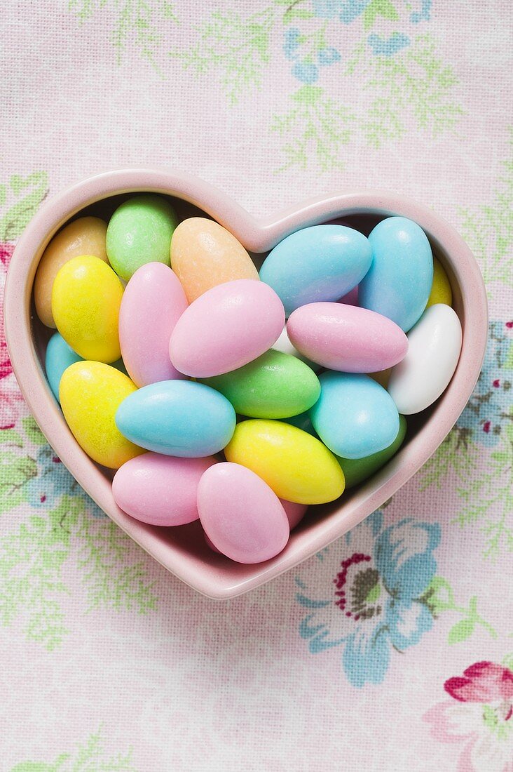 Coloured sugared almonds in pink heart-shaped dish
