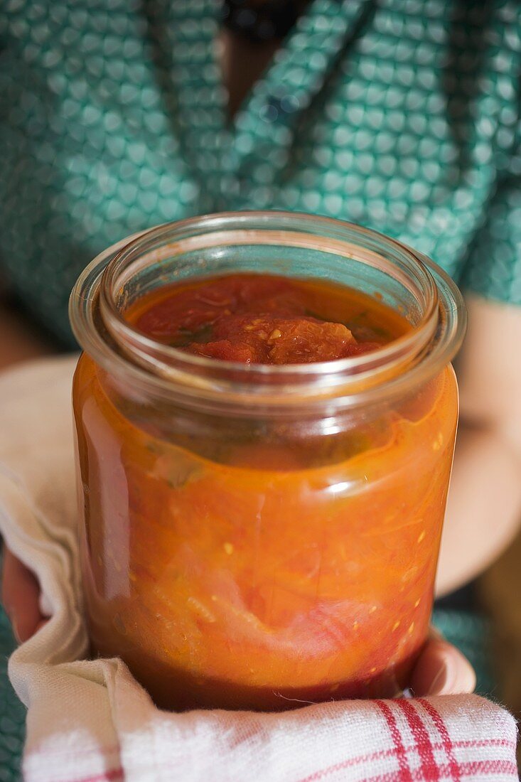 Frau hält Einmachglas mit Tomatensauce