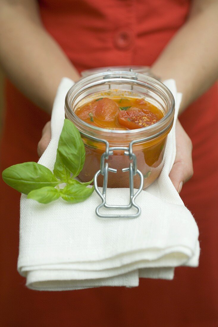 Hände halten Einmachglas mit Tomatensauce