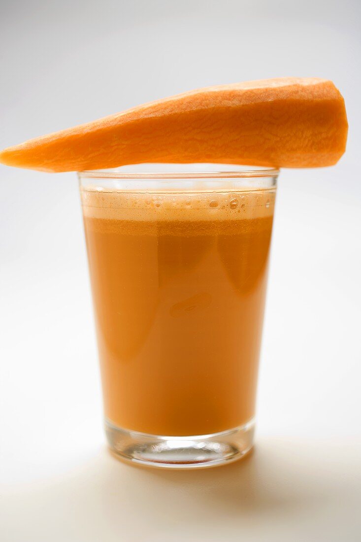 Fresh carrot on a glass of carrot juice