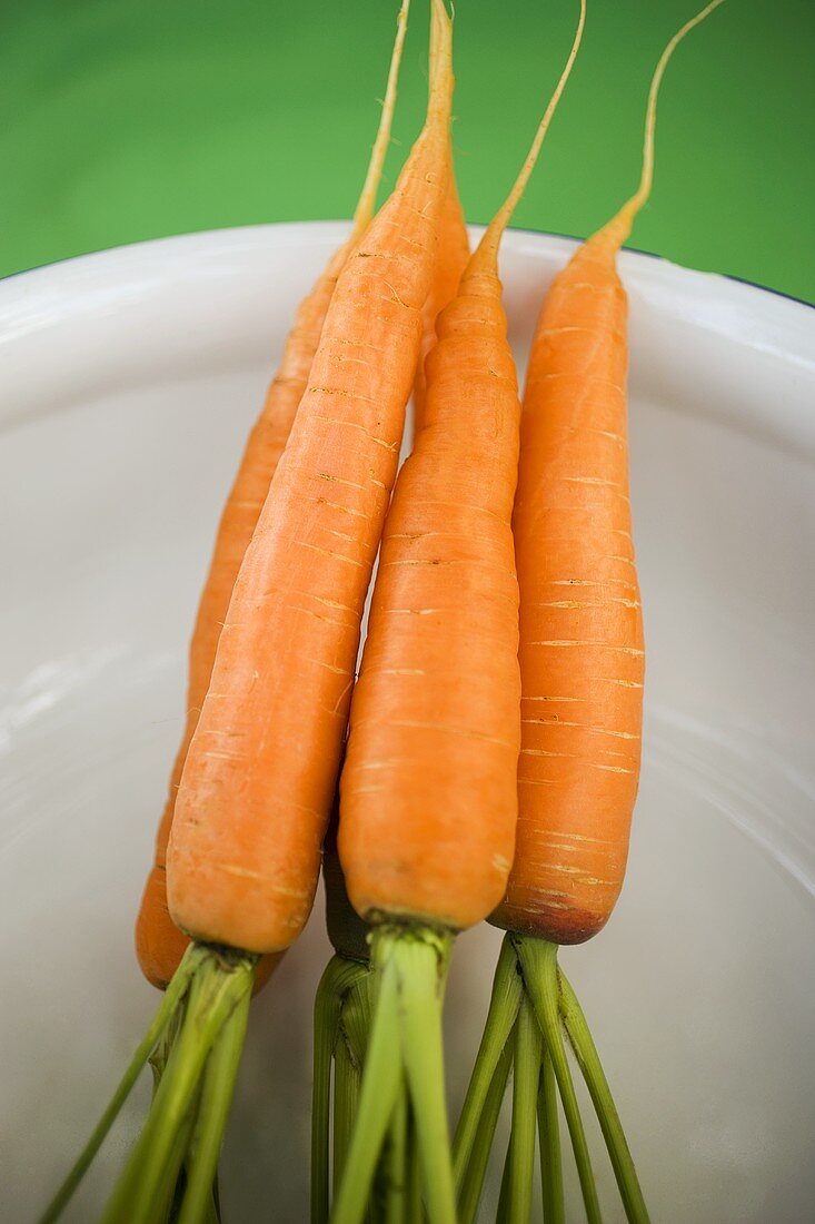 Fresh carrots in white bowl (overhead view)