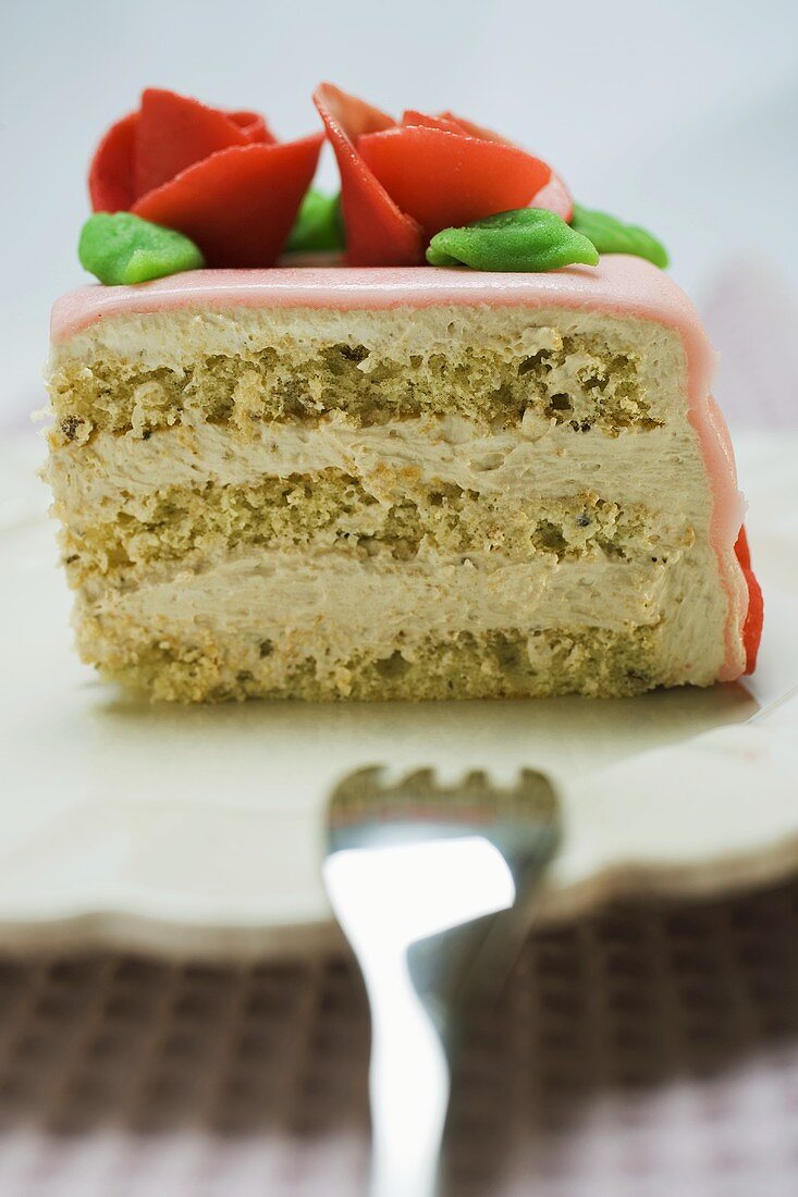 Piece of birthday cake with marzipan roses on plate