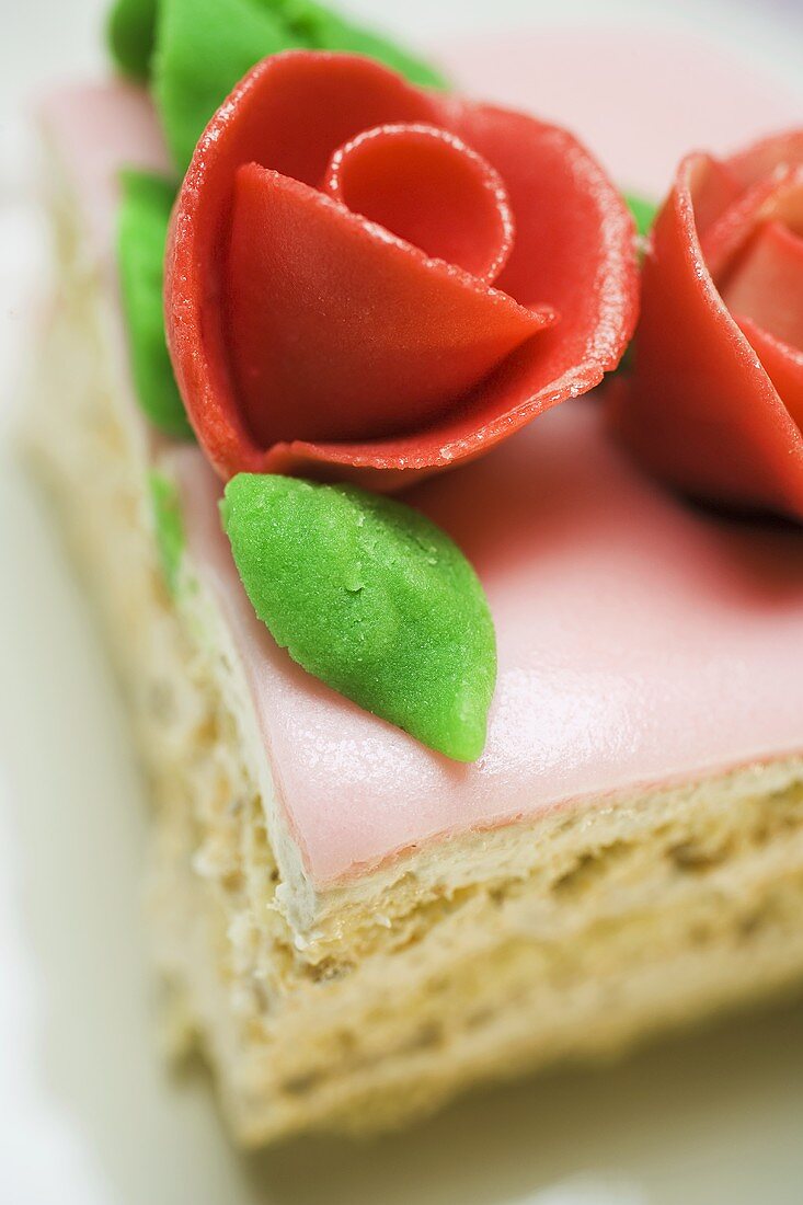 Piece of birthday cake with marzipan roses (close-up)
