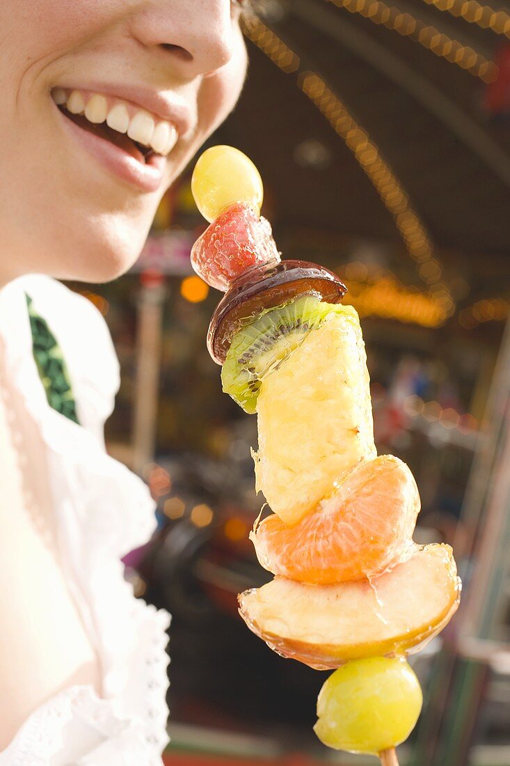 Woman holding skewered candied fruit (Oktoberfest, Munich)