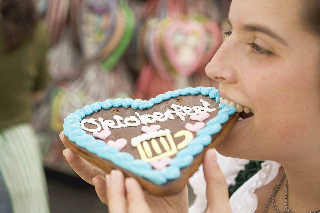 Frau beisst in Lebkuchenherz (München, Oktoberfest)