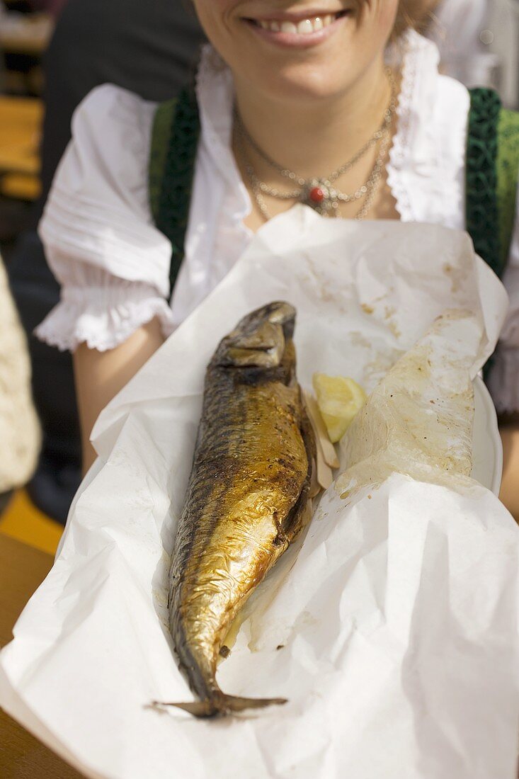Woman holding Steckerlfisch (fish on stick, Oktoberfest, Munich)