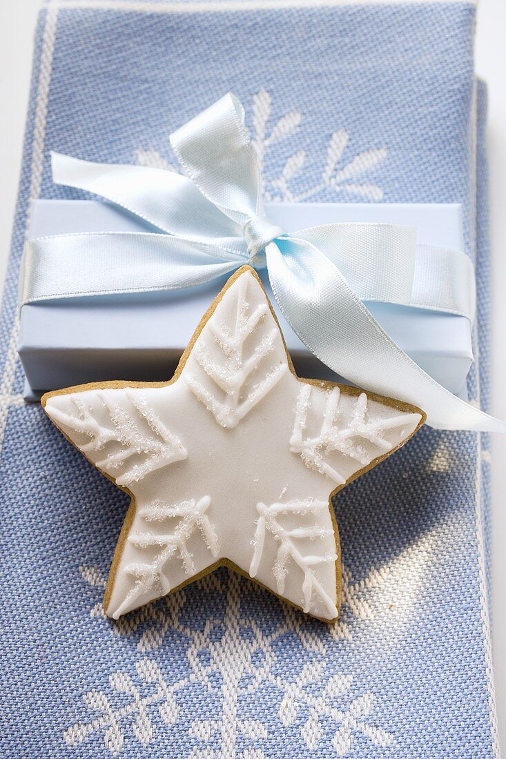 Lebkuchenstern mit weisser Zuckerglasur vor Geschenk