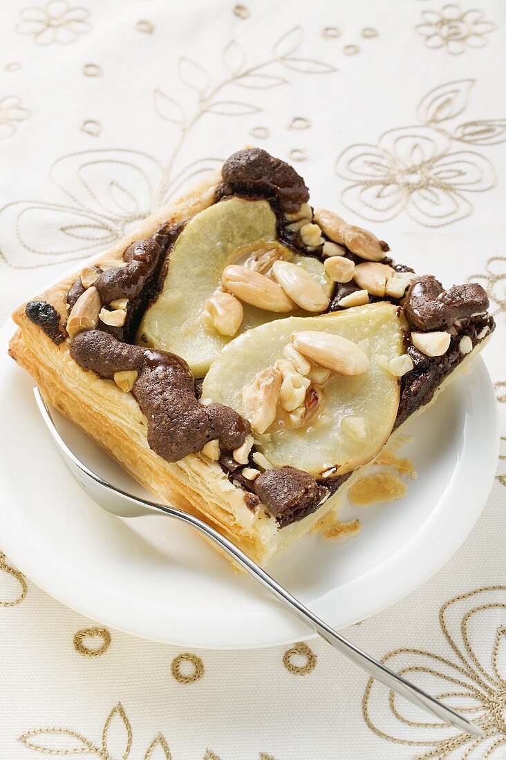 Piece of pear and chocolate tart with almonds on plate