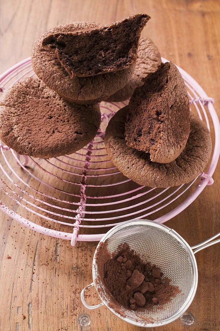 Chocolate buns on cake rack, cocoa powder in sieve