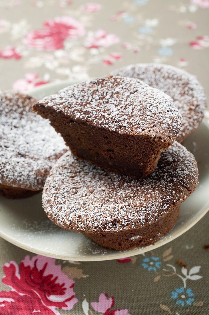 Chocolate buns with icing sugar, one halved