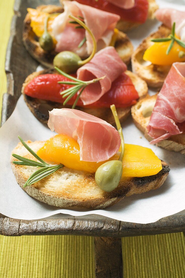 Crostini with raw ham, peppers and giant capers