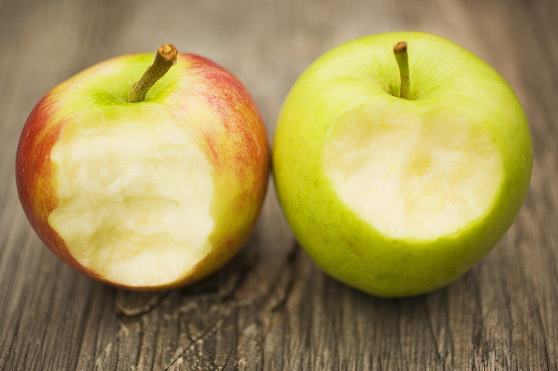 Zwei angebissene Äpfel auf Holzuntergrund