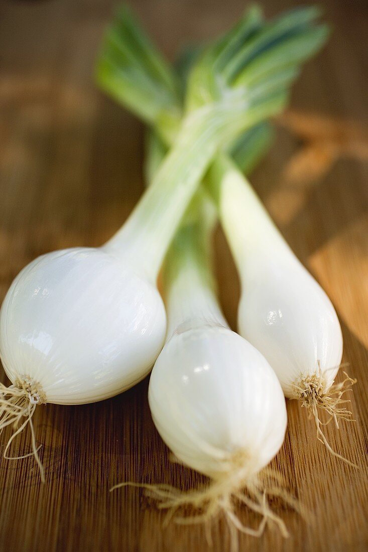 Three spring onions on wooden background