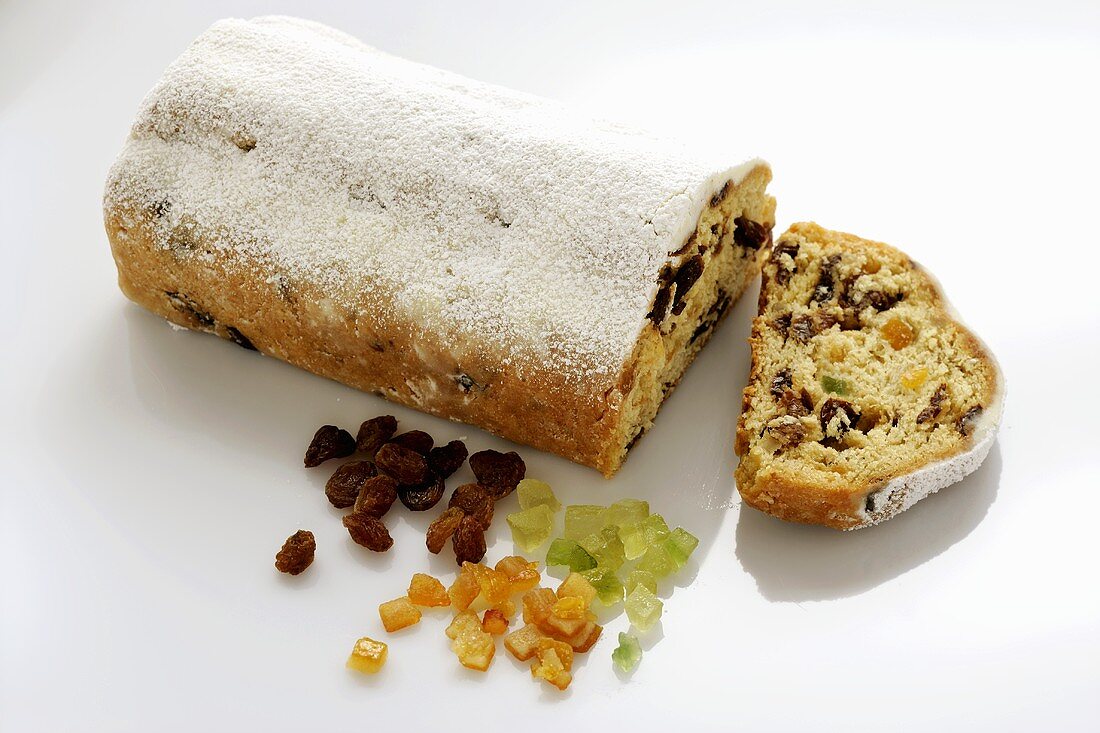 Stollen with icing sugar, a slice cut, and ingredients