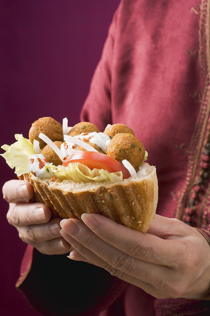 Frau hält Fladenbrot mit Falafel (Kichererbsenbällchen)