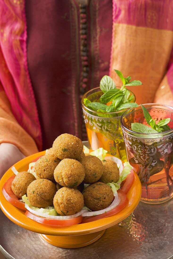 Woman holding tray of falafel (chick-pea balls) and tea