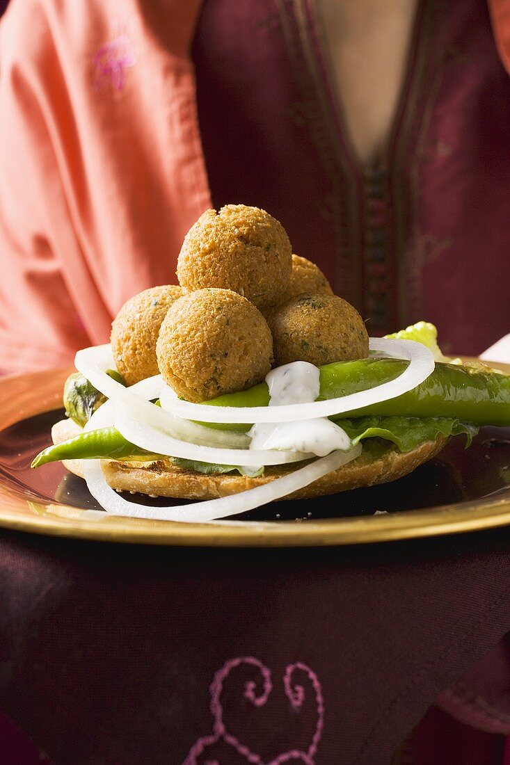 Woman serving falafel (chick-pea balls) with vegetables